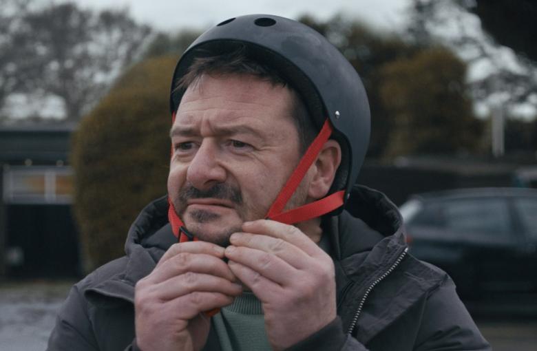'The Beginner' - man puts on his helmet to practice skateboarding...